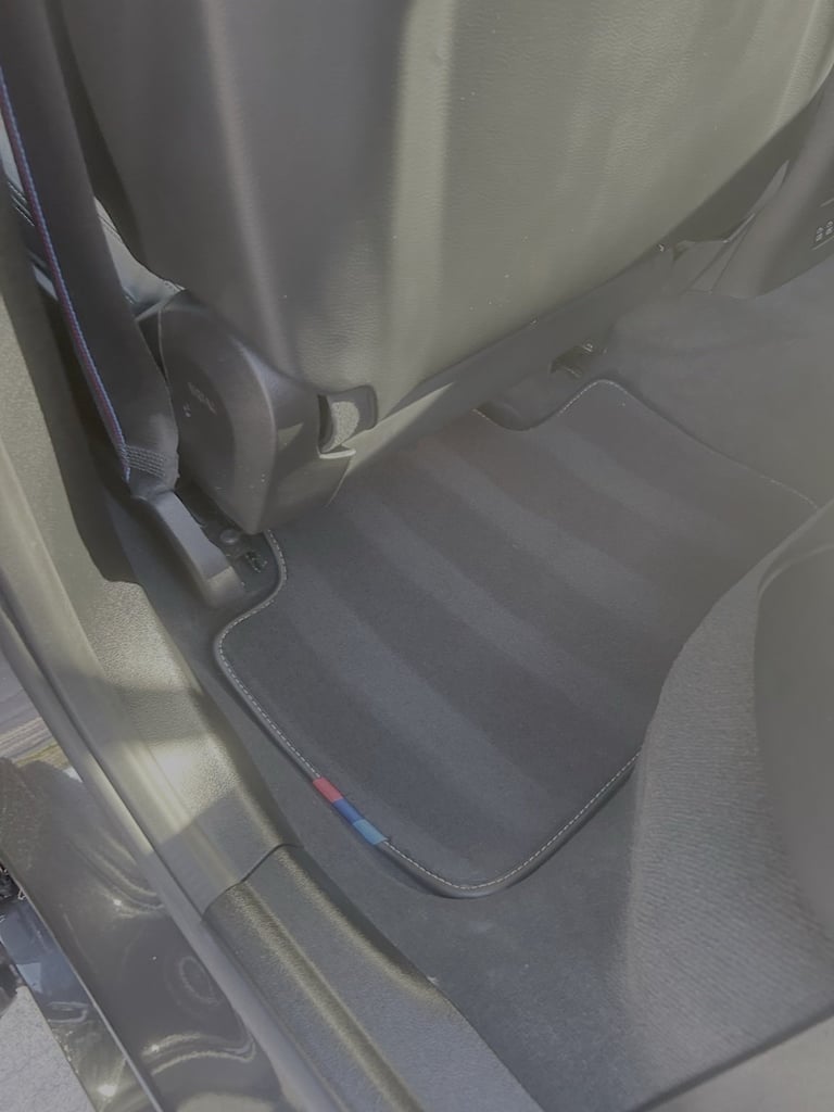 Rear car seat viewed from above, showing dark gray cloth upholstery and seat structure in vehicle interior