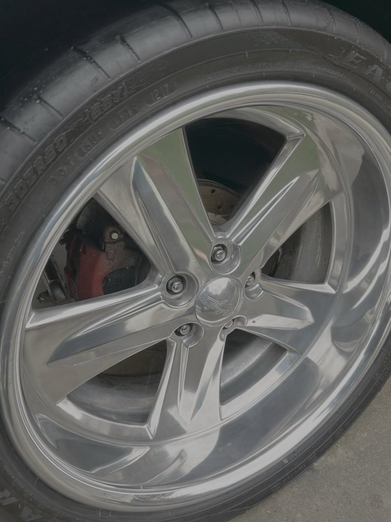 Close-up of a polished silver custom car wheel with multi-spoke alloy rim design and performance tire